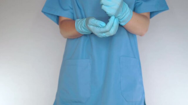 Doctor in blue medical uniform and protective gloves standing on white background and holding stack of coins in hands, female doctor showing her meager salary in hospital. Global collapse in medical