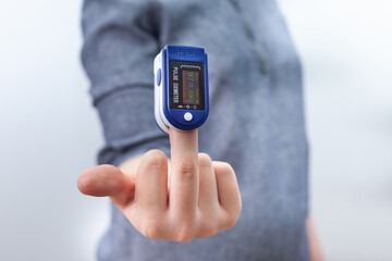 Woman showing middle finger with oximeter. Fuck you coronavirus concept