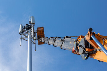 Crane with telescopic boom lift used as an aerial working platform. Worker install cellular base...