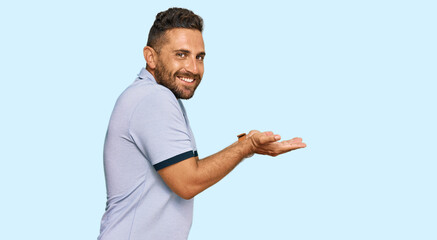 Handsome man with beard wearing casual clothes pointing aside with hands open palms showing copy space, presenting advertisement smiling excited happy