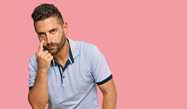 Handsome man with beard wearing casual clothes pointing to the eye watching you gesture, suspicious expression