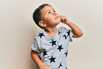 Adorable latin toddler wearing casual clothes thinking concentrated about doubt with finger on chin...