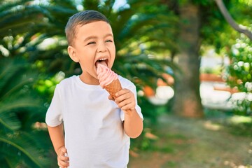 Adorable hispanic boy smiling happy eating ice cream at the park. © Krakenimages.com