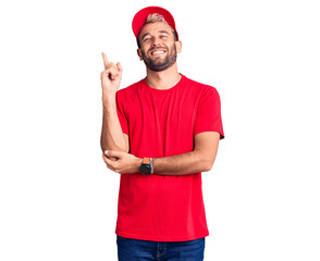 Naklejka premium Young handsome blond man wearing t-shirt and cap with a big smile on face, pointing with hand and finger to the side looking at the camera.