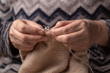 woman hands knitting wool yarn with knitting needles
