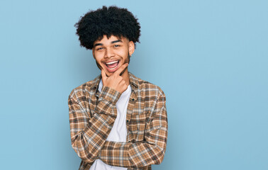 Fototapeta na wymiar Young african american man with afro hair wearing casual clothes looking confident at the camera smiling with crossed arms and hand raised on chin. thinking positive.