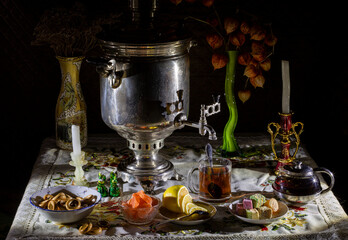 Evening tea from a samovar by candlelight with lemon and sweets.