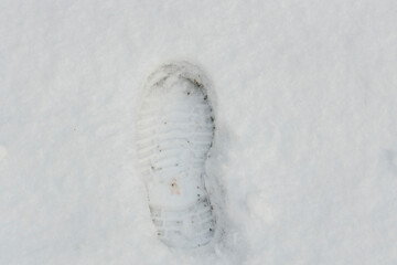 Close up view of shoe print on snowy asphalt road. Winter season concept.