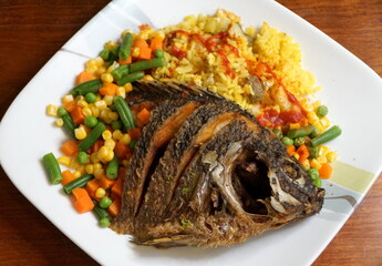 Fried tilapia with yellow rice, hot sauce and mixed vegetable