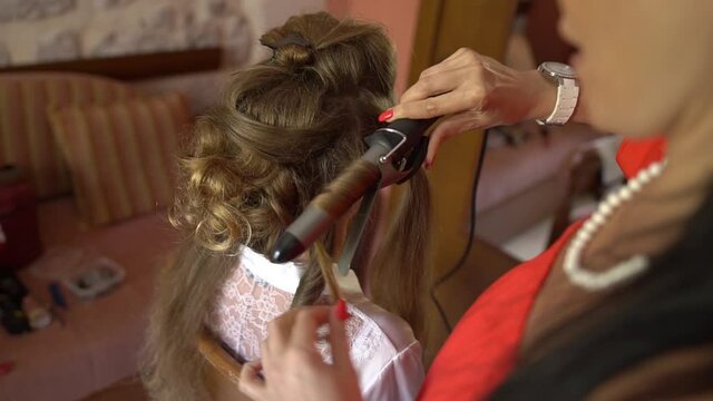 the stylist makes the bride's hair while getting ready before wedding ceremony