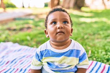 Adorable african american toddler sitting on the grass at the park.