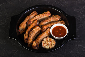 Sliced baked pork ribs in a baking dish with garlic and red sauce