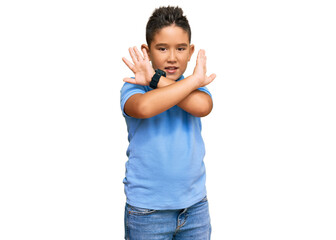 Little boy hispanic kid wearing casual clothes rejection expression crossing arms doing negative sign, angry face