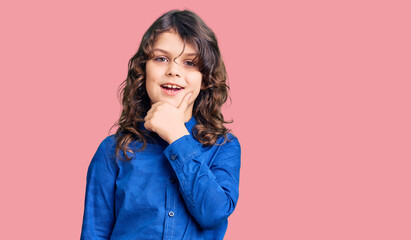 Cute child with long hair wearing casual clothes looking confident at the camera with smile with crossed arms and hand raised on chin. thinking positive.