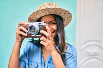 Young latin tourist girl on vacation smiling happy using vintage camera at the city.