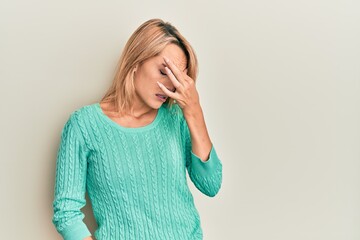 Beautiful blonde woman wearing casual winter sweater tired rubbing nose and eyes feeling fatigue and headache. stress and frustration concept.