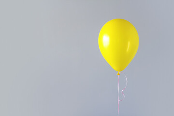 A yellow balloon against a gray wall copy space.