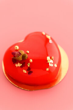 A cake in heart shape. Red cupcake in the shape of a heart on a pink background. Valentine's Day. Vertical photo