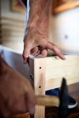 Carpenter hobbyist assembling wooden boards at home / garage.