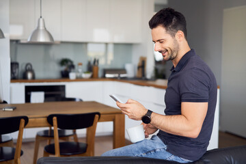 Happy man at home using mobile phone