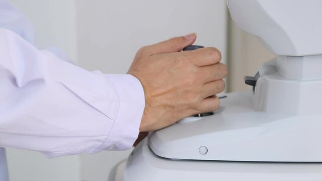 Hand of ophthalmologist control joystick of the optical refractometer machine for examing optic of eyes. 