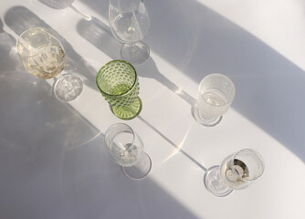 Transparent and green wine glasses and their shadows on a white background