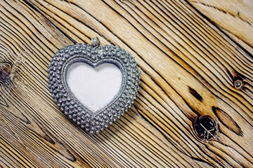 Heart photo frame background. A decorative silvery heart with a place for text on a wooden light table. Concept background for valentine's day, wedding, romantic invitation. Copy space