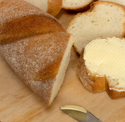 Fresh baguettes with crispy crust with butter  chopped on a cutting board on a white table. Tasty breakfast. kitchen knife. High quality photo
