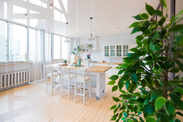 Stylish kitchen in light colors in a trendy modern duplex apartment with large high windows.