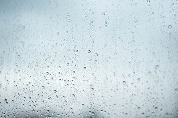 Rainy drops on window glass with sky background
