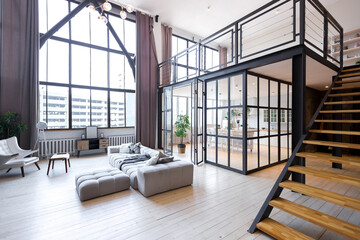 trendy modern design two-level apartment with large high windows. The stylish living room and kitchen in bright colors are undressed by a glass partition. bedroom on the second floor.