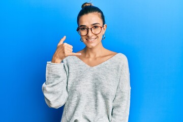 Young hispanic woman wearing casual clothes smiling doing phone gesture with hand and fingers like talking on the telephone. communicating concepts.