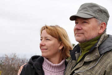 Smiling middle-aged man and woman standing hugging in nature