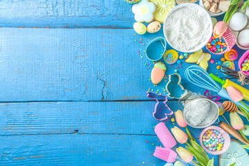 Easter baking background with rolling pin, whisk, eggs, flour and colorful sugar confetti on blue wooden table top view. Flat lay with copy space for text