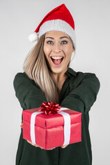 young blond girl with Santa hat and red gift/present ist surprised an smiles