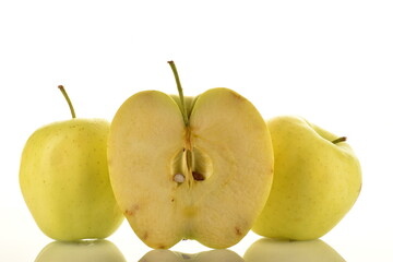 One half and two whole juicy yellow apples, close-up, on a white background.