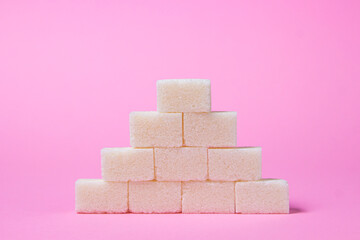 Sugar cubes on a pink background. Sugar pyramid. Refined sugar.