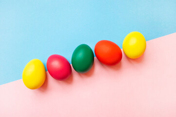 colorful easter eggs on pink and blue background with copy space. Easter background