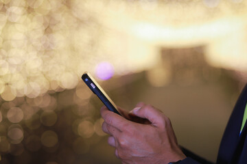 close up  shot of a businessman using a smartphone to communicate via social media at night in the city. It has a beautiful blurred background.