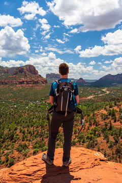 A young man stands on an edge of the rock after successfully completing a hike. A beautiful and breathtaking view over red rocks of Sedona - Arizona seen from a lookout point above the city