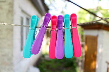 A set of multi-colored pins hanging on a rope on the street. Turquoise, pink and purple pins on a rope