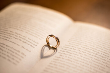 Two wedding Ring on the bible with shadow of heart shape on the open page. Engagement, wedding and...