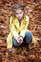 Little beautiful girl in a yellow raincoat walks in the  park.