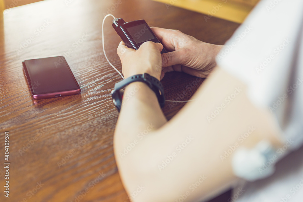 Wall mural Modern diabetes treatment, woman checking glucose level and dosing insulin using insulin pump and remote sensor on her hand