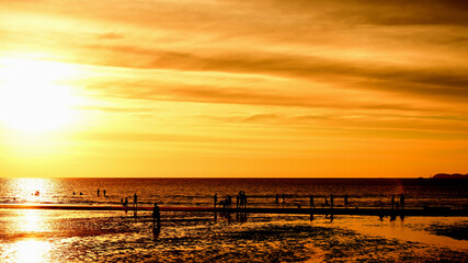 Sunset at the beautiful beach view Among the many people come to play in the sea before the dusk.silhouette of sunset at beach.