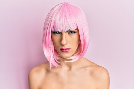 Young man wearing woman make up wearing pink wig skeptic and nervous, frowning upset because of problem. negative person.