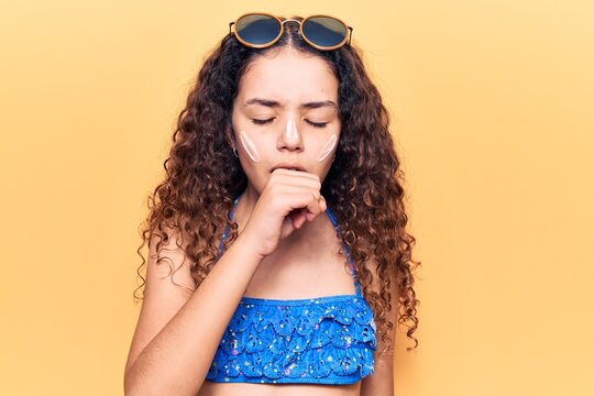 Beautiful kid girl with curly hair wearing bikini and sunglasses feeling unwell and coughing as symptom for cold or bronchitis. health care concept.