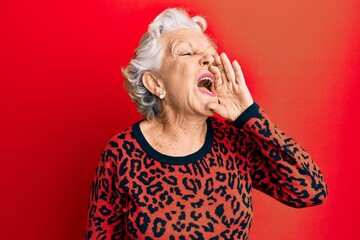 Senior grey-haired woman wearing casual clothes shouting and screaming loud to side with hand on mouth. communication concept.