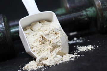 Dry protein in a spoon and old iron dumbbells.