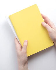 In the hands of two notepads, yellow and white. Education and business concept. Place for an inscription, minimalism